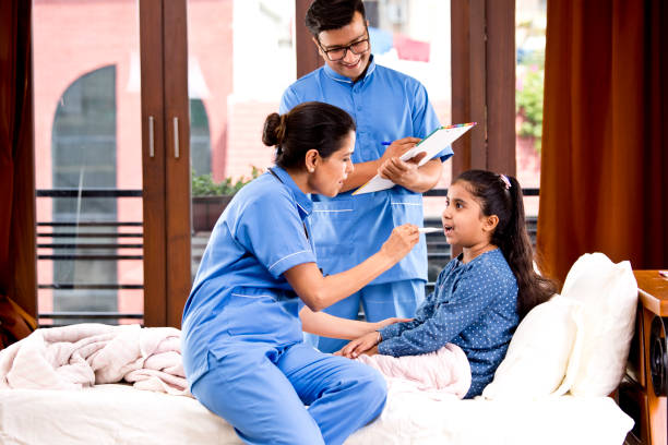 Nursing staff checking temperature of girl using thermometer at home